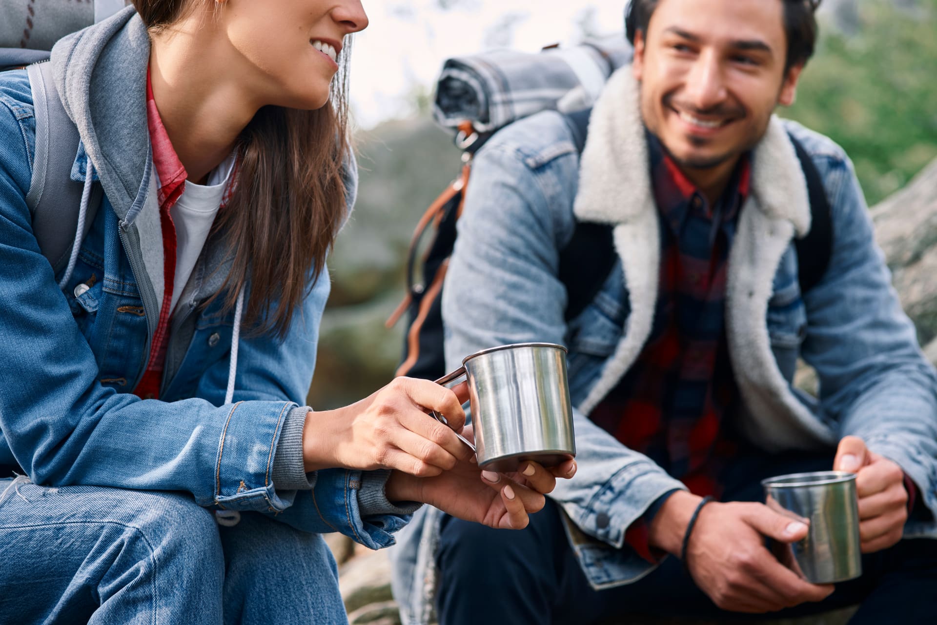 Two backpackers with coffee in stainless steel cups during a hike break